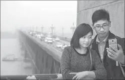  ?? JIAN HUA / FOR CHINA DAILY ?? People take a selfie against the backdrop of the Nanjing Yangtze River Bridge on Sunday. The bridge will be closed for 27 months for repairs, starting on Friday next week.