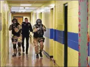  ?? ASSOCIATED PRESS ?? Members of the Washington County Sheriff’s Office and the Hudson Falls Police Department use unloaded guns to take part in an emergency drill as they walk through a corridor inside the Hudson Falls Primary School in Hudson Falls, N.Y.