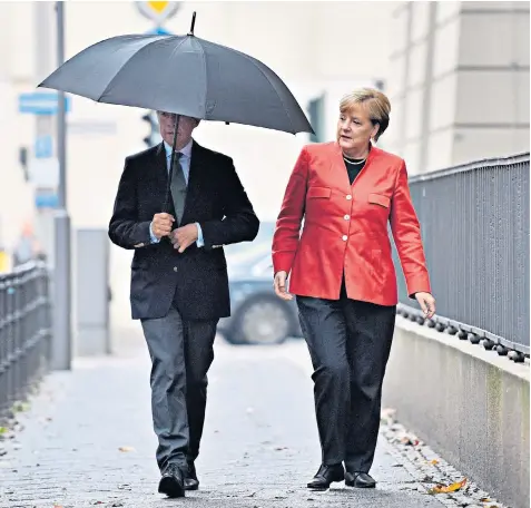  ??  ?? Chancellor Angela Merkel, above with husband Joachim Sauer on their way to cast their vote, acknowledg­ed the challenges of the dramatic gains for AFD