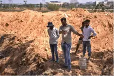  ?? ?? Anand Malligavad (second le ) speaking to workers at a constructi­on site near the arid Doddathogu­r lake in Bengaluru.