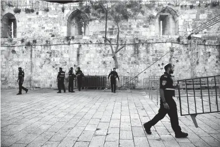 ?? Associated Press ?? n Israeli police officers walk Tuesday outside the Al-Aqsa Mosque compound in Jerusalem’s Old City. Amid widespread Muslim protests, Israel has begun dismantlin­g metal detectors it installed a week earlier at the gates of a contested Jerusalem shrine.