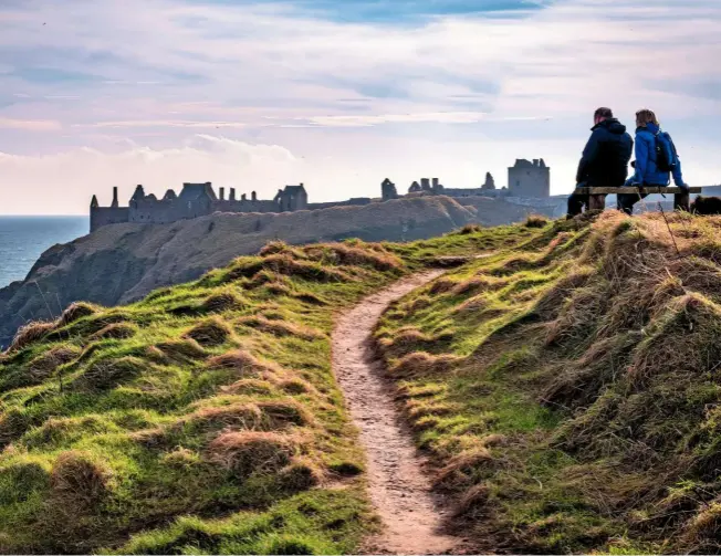  ??  ?? Walkers resting by the path as Dunnottar Castle comes into view. The surviving buildings are mainly from the 15th and 16th centuries, but the fortificat­ions originated from the Middle Ages. The name Dunnottar comes from the Gaelic ‘Dùn Fhoithear’, meaning ‘fort on the shelving slope’.