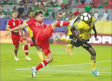  ?? The Associated Press ?? Canada’s Michael Petrasso leaps to strike the ball as Jamaica’s Kemar Lawrence heads it out of harm’s way during CONCACAF Gold Cup quarter-final action on Thursday in Glendale, Ariz. Jamaica won the match 2-1 and advances to the semifinal.