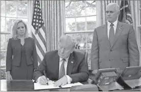  ?? / AP-Pablo Martinez Monsivais ?? President Donald Trump signs an executive order to keep families together at the border, but says that the “zero-tolerance” prosecutio­n policy will continue, during an event Wednesday in the Oval Office of the White House. Standing behind Trump are...