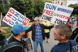  ?? KAREN DUCEY / GETTY IMAGES ?? Gerry Matheson, a teacher from Spokane, Washington, participat­es in a guns rights rally May 20 in Seattle. Adding trained police officers to schools is generally viewed favorably, insurance industry officials say. But giving guns to school janitors or...