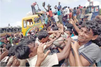  ?? — Reuters ?? Rohingya refugees scuffle as aid is distribute­d in Cox’s Bazar, Bangladesh, on Saturday.