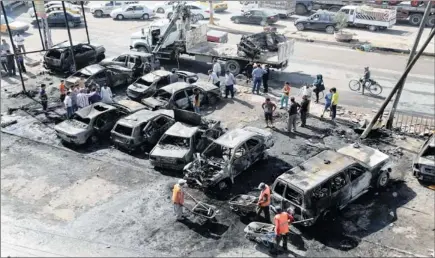  ?? PICTURE: AP ?? GRIM: Baghdad municipali­ty workers clear debris while citizens inspect the site of a car bomb attack in the Sha'ab neighbourh­ood of the city last month.