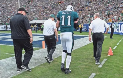  ??  ?? Eagles quarterbac­k Carson Wentz is escorted off the field after injuring his knee in the second half of the Eagles’ 43-35 win over the Rams at Los Angeles Memorial Coliseum. ROBERT HANASHIRO/USA TODAY SPORTS