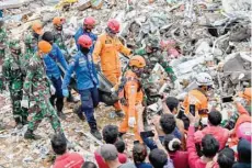  ?? — AFP ?? Rescuers move the body of a victim that was trapped in a collapsed building in Mamuju a day after a 6.2-magnitude earthquake rocked Indonesia’s Sulawesi island.