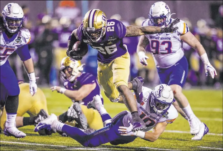  ?? L.E. Baskow Las Vegas Review-Journal @Left_Eye_Images ?? Washington running back Salvon Ahmed (26) breaks free of a diving tackle attempt by Kekoa Nawahine (10) of No. 18 Boise State in the Las Vegas Bowl on Saturday night.