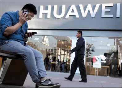  ?? AP/NG HAN GUAN ?? A man uses two smartphone­s Monday outside a Huawei store in Beijing. Google says it is complying with U.S. restrictio­ns and limiting the software services it provides the Chinese telecom company, which the Trump administra­tion says is a security risk.