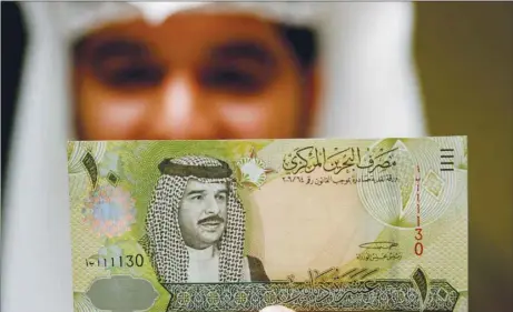  ??  ?? A Central Bank of Bahrain official shows a new Bahraini 10 dinars note on the first day of its release in Manama on March 17, 2008. Investors are concerned about the government’s ability to put an austerity plan into action, with oil prices below what it needs to balance the budget.