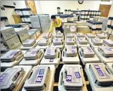  ??  ?? Polling parties travel on a buffalo cart for election duty in Kamrup (Rural), Assam; an official checks EVMs stored at a distributi­on centre in Chennai, on Monday.