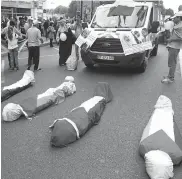  ??  ?? Fake dead bodies wrapped in Palestinia­n flags lie in a Paris street, as pro- Palestinia­n demonstrat­ors chant antiIsrael­i slogans on Saturday. —