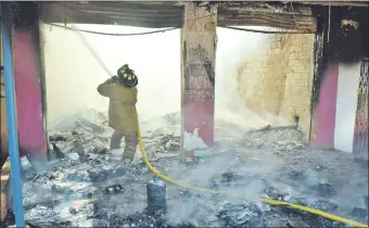  ??  ?? Un bombero procede al trabajo de enfriamien­to de la estructura del establecim­iento. Mercadería­s valuadas en unos G. 500.000.000 quedaron reducidas a cenizas.