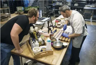  ?? STAFF PHOTOS BY TROY STOLT ?? Sweet and Savory Classroom instructor Jeff Pennypacke­r, right, teaches a cooking class through the video app Zoom as his coworker, Ted Marris, records close-up action.