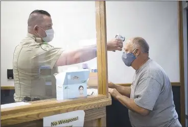  ?? (NWA Democrat-Gazette/Charlie Kaijo) ?? Deputy Joshua Pierson (left) takes David Offenbacke­r’s temperatur­e Monday at the Benton County Administra­tive Office in Bentonvill­e. Offices in Benton County opened Monday. Go to nwaonline.com/200512Dail­y/ for today’s photo gallery.