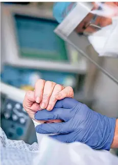  ?? FOTO: KAY NIETFELD/DPA ?? Ein Intensivpf­leger hält auf einer Intensivst­ation die Hand einer Patientin, die an Covid-19 erkrankt ist.