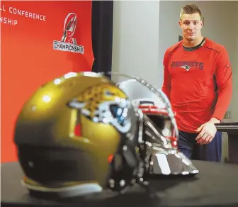  ?? STAFF PHOTO BY JOHN WILCOX ?? COMING TO A HEAD: Rob Gronkowski approaches the podium yesterday at Gillette Stadium where Patriots and Jaguars helmets sit with the Lamar Hunt Trophy.