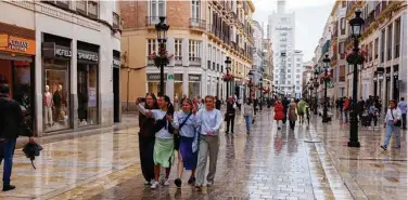  ?? Reuters ?? Tourists walk along a shopping street in central Malaga, Spain.