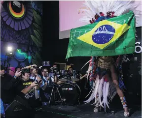  ?? NELSON ALMEIDA / AFP / GETTY IMAGES ?? Rosie Oliveira holds a Brazilian flag with a slogan promoting the ouster of the country’s president during the pageant in Sao Paulo.