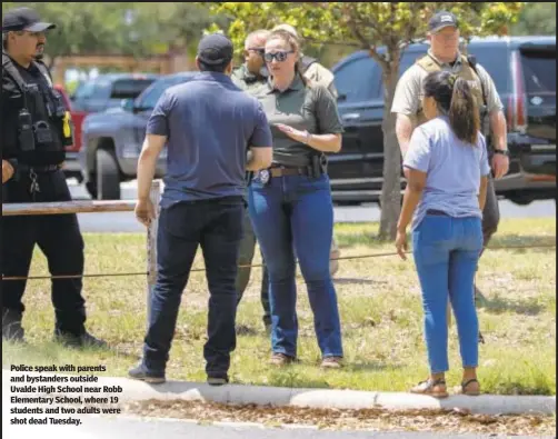  ?? ?? Police speak with parents and bystanders outside Uvalde High School near Robb Elementary School, where 19 students and two adults were shot dead Tuesday.