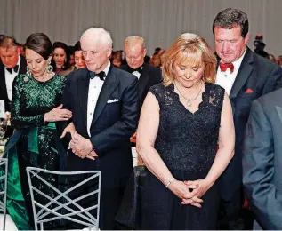  ?? [PHOTO BY NATE BILLINGS, THE OKLAHOMAN] ?? Former Gov. Mary Fallin and husband Wade Christense­n pray next to former Gov. Frank Keating and wife Cathy Keating during the inaugural ball for Gov. Kevin Stitt at the Cox Convention Center in Oklahoma City on Monday night.
