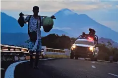  ?? ?? Un indocument­ado camina por la carretera, seguido por un vehículo de la Guardia Nacional mexicana