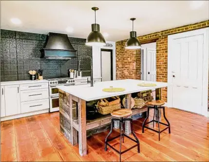  ?? ?? Cynthia and River Ward removed plaster to expose the interior brick wall and added all new cabinetry, quartz countertop­s and an island made from beans and planks pulled from a barn razed on property.