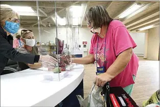  ?? PHOTOS BY ALEX HORVATH / THE CALIFORNIA­N ?? The Kern County Library’s West Kern Area Regional Supervisor Sherry Wade, left, and library aide Lisa Boyd assist Pamela Bishop as she checks out books at Oildale’s Rathbun branch library. Bishop was the library’s first patron when the branch resumed service Wednesday after being closed for 17 months for repairs and remodeling.