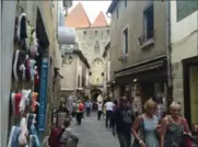 ??  ?? Visitors walk through a gauntlet of tourist shops in the medieval city of Carcassonn­e.