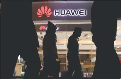  ?? AP PHOTO/NG HAN GUAN ?? Pedestrian­s walk past a Huawei retail shop in Beijing on Thursday. China has demanded that Canada release a Huawei Technologi­es executive who was arrested in a case that adds to technology tensions with Washington and threatens to complicate trade talks.