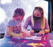  ??  ?? Tampa residents Kalea Kazbour, 5, and her mom, Lisa Kazbour, work on coloring in satellites Jan. 4 at Planet Play, part of Kennedy Space Center Visitor Complex.