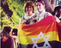  ?? (Courtesy) ?? SARAH WEIL (right) and Jewish educator and trans-activist Yiscah Smith wrap themselves in a flag at the rally in Jerusalem Saturday night.