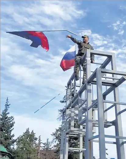  ?? REUTERS ?? Un militar ucraniano quita las banderas rusas en el centro de Limán para colocar la ucraniana.