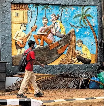  ??  ?? A man wearing a mask walks past a mural near the Candolim beach on the Arabian Sea coast in Goa. The unspoken fear of the coronaviru­s is sapping Goa’s vibrant beach shacks and noisy bars of their lifeblood. — Ti Gong