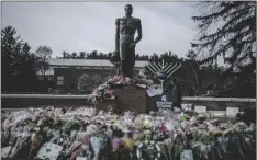  ?? JOURNAL VIA AP JAKE MAY/THE FLINT ?? Hundreds of flowers overflow from the base of the Spartan Statue as campus opens back up for the first day of classes on Feb. 20 at Michigan State University in East Lansing, Mich., one week after three students were killed and five others injured during a mass shooting at the university.