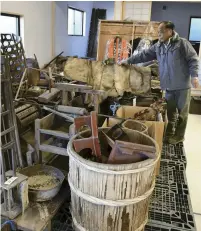  ?? The Yomiuri Shimbun ?? Shigeru Sasaki examines exhibit items relocated to a new facility in the Sakata district of Namie, Fukushima Prefecture.