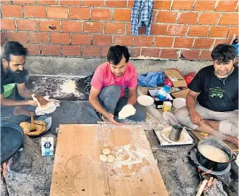  ??  ?? Das bosnische Rote Kreuz versorgt die Migranten mit Essen (oben), zusätzlich backen sie sich selbst Brot. Schwierig ist, dass es nur einen Stromgener­ator gibt.