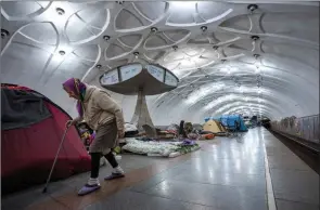  ?? The Associated Press ?? An elderly woman walks inside a metro station being used as a bomb shelter in Kharkiv, Ukraine, on Thursday.