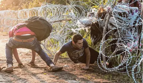  ?? Symbolfoto: Sandor Ujvari, MTI/dpa ?? Auf der Suche nach einem besseren und sicheren Leben flüchten viele Menschen und überwinden dabei auch Sperren aus Stacheldra­ht wie an der Grenze zwischen Ungarn und Serbien. Beim Projekt „Freilig“berichten junge Menschen, die heute in Deutschlan­d...