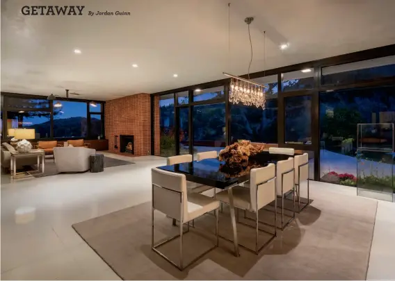  ?? By Jordan Guinn JACOB ELLIOTT PHOTOGRAPH­Y ?? The open floor plan features a brick fireplace in the living area, floortocei­ling windows and a contempora­ry chandelier in the dining area.