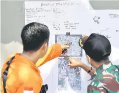  ??  ?? Rescue team members point to a map as they try to recover dead bodies after an earthquake hit Petobo neighbourh­ood in Palu, Indonesia.