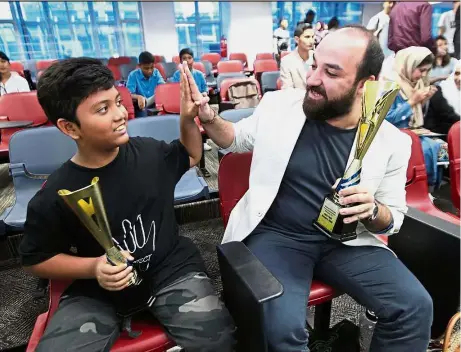  ??  ?? Reason to cheer: Mohd Feroz (left) and Mohd Mwaffaq high-fiving each other after they won the top spots in the Migrant and Refugee Poetry Competitio­n 2017.