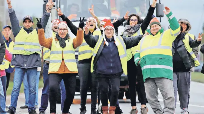  ??  ?? ► Activistas de los Chalecos Amarillos posan frente a un camión, en Gaillon, Francia.