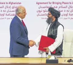  ?? REUTERS ?? Mullah Abdul Ghani Baradar, leader of the Taliban delegation (right) and Zalmay Khalilzad, US envoy for peace, shake hands after the peace pact is signed.