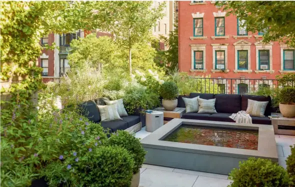  ??  ?? This page: A water feature and flourishin­g greenery create a calming rooftop sanctuary; a view of the townhouse’s redbricked facade Opposite page, clockwise from top: The master bedroom incorporat­es a vintage sofa and handcrafte­d four-poster bed; sage green walls work as a striking foil in the master bathroom, which also features oak drawers as well as a vanity and shower area clad in beautifull­y veined marble