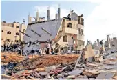  ??  ?? Palestinia­ns gather around the ruins of buildings which were destroyed in Israeli air strikes on Thursday