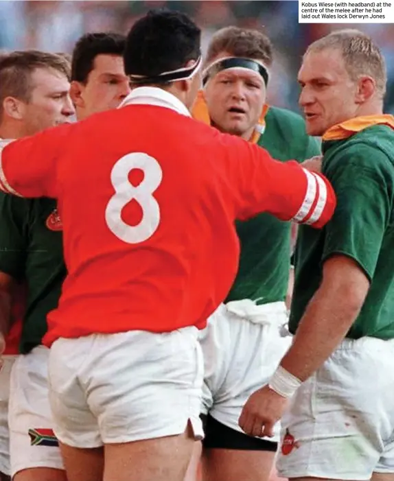  ?? ?? Kobus Wiese (with headband) at the centre of the melee after he had laid out Wales lock Derwyn Jones