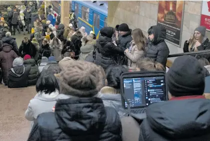  ?? Photos / AP ?? Above: Ukrainians take shelter in a Kyiv subway station during a rocket attack. Left: Vladimir Putin personally attended the reopening of the Crimean bridge damaged in a truck bomb attack.